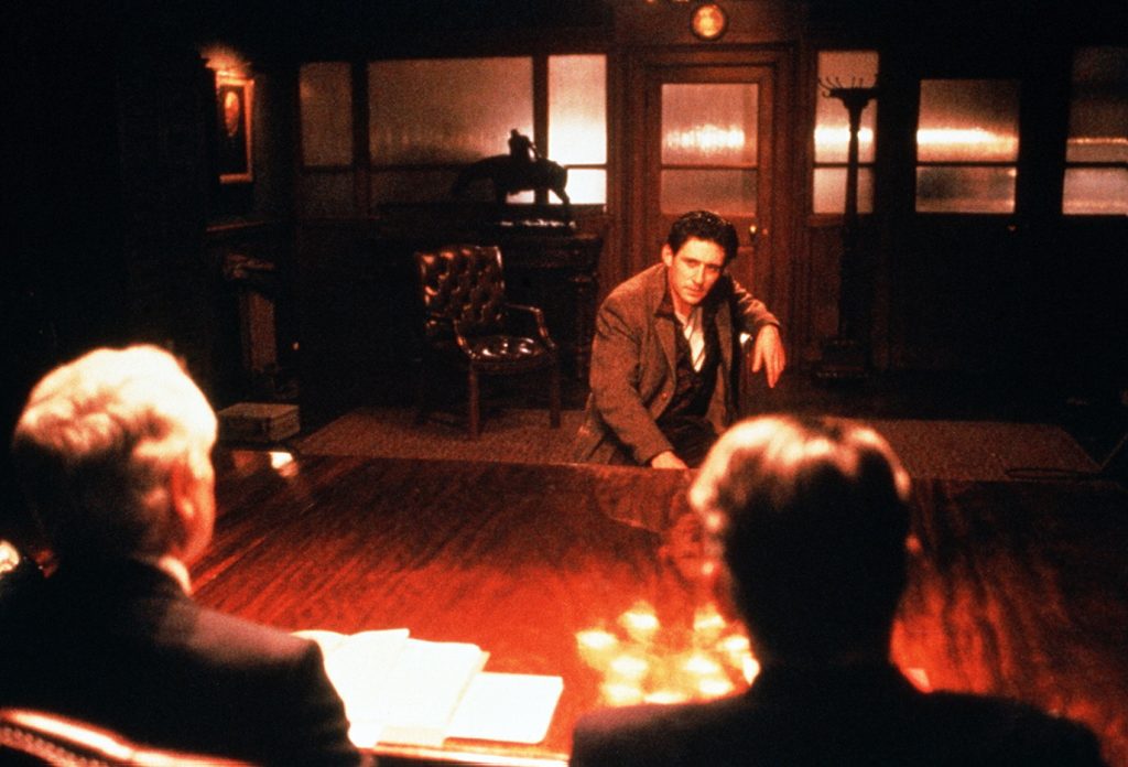 Still from the film Defence of the Realm. A white man is facing two other white men in a government office
