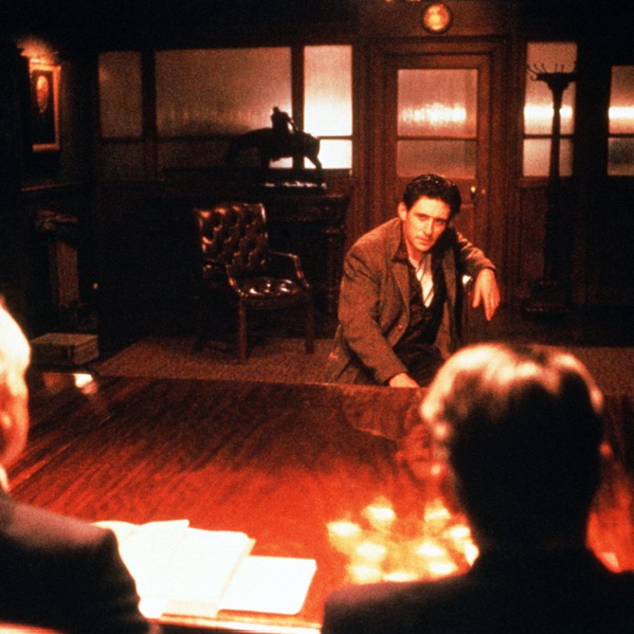 Still from the film Defence of the Realm. A white man is facing two other white men in a government office