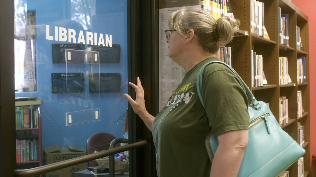 A librarian standing at a door with some books behind her