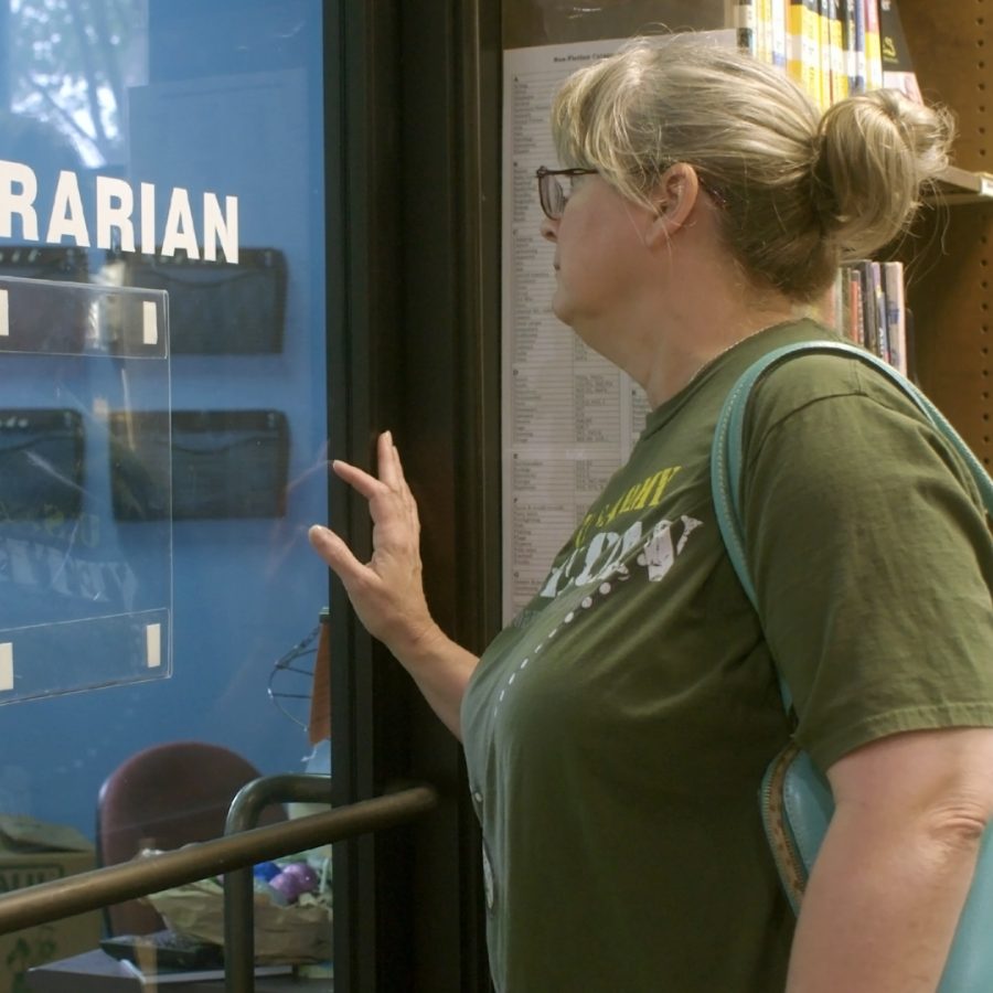 A librarian standing at a door with some books behind her