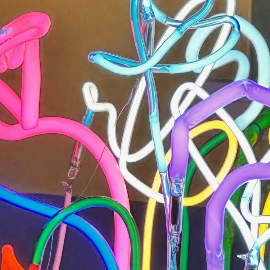 The image shows a closeup of colourful pieces of lit neon glass tubes overlapping each other