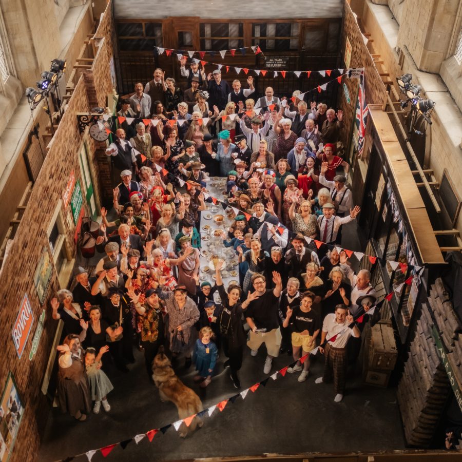 Images show a group of people in 1940s clothes around a street party with bunting