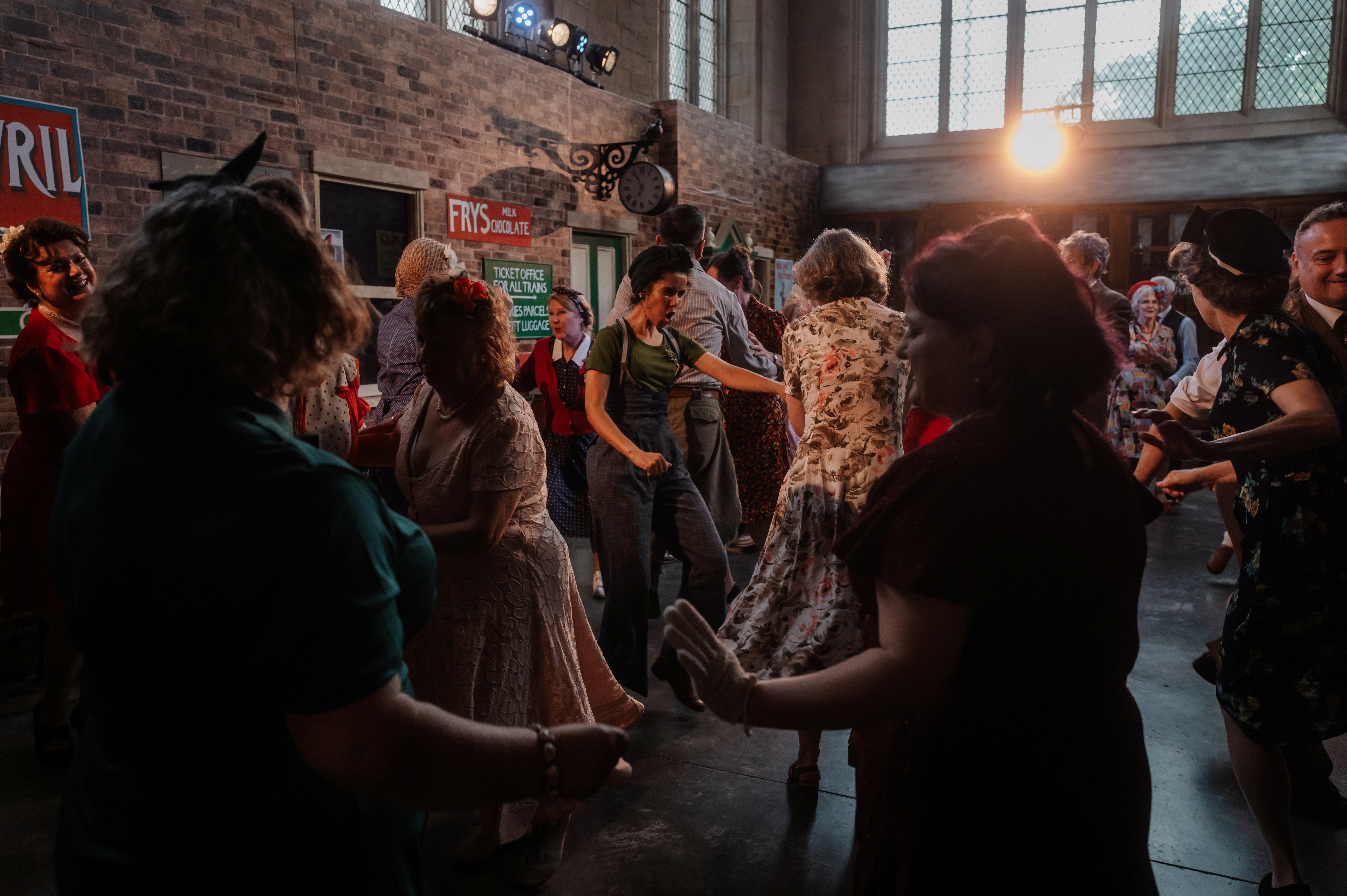 Images show a group of people in 1940s clothes dancing in the Lindy Hop style in a train station filmset at 20-21 Visual Arts Centre